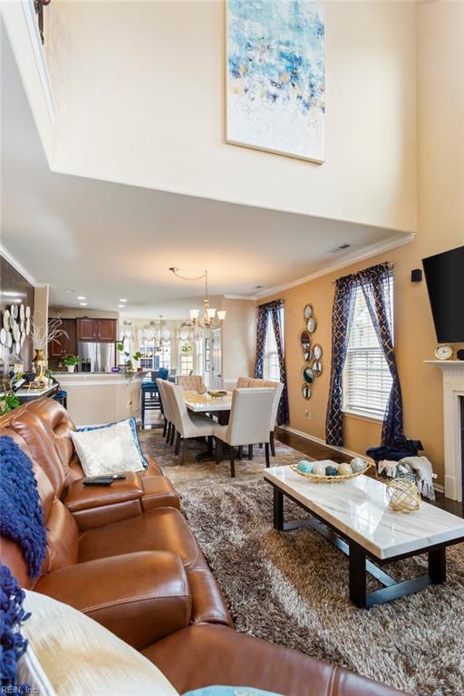 living room with crown molding and an inviting chandelier