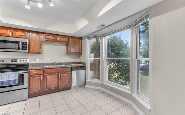 kitchen with appliances with stainless steel finishes, light tile patterned floors, a raised ceiling, and sink