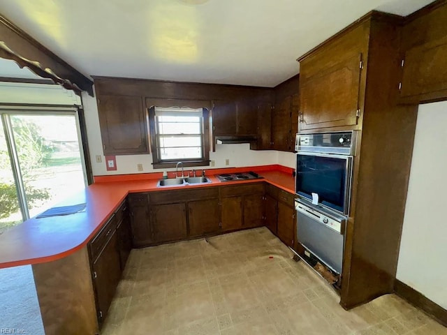 kitchen with oven, sink, wall oven, kitchen peninsula, and stainless steel gas cooktop