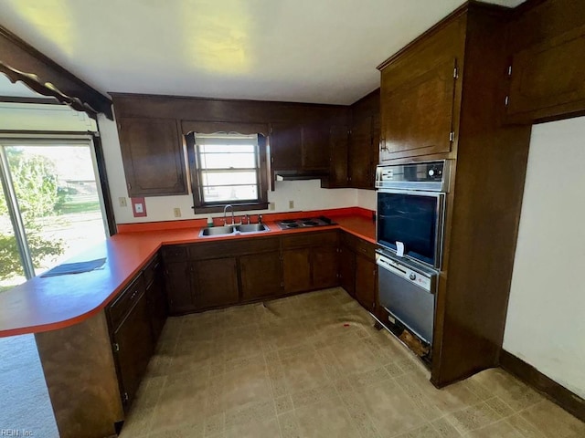 kitchen featuring plenty of natural light, kitchen peninsula, sink, and stainless steel gas cooktop