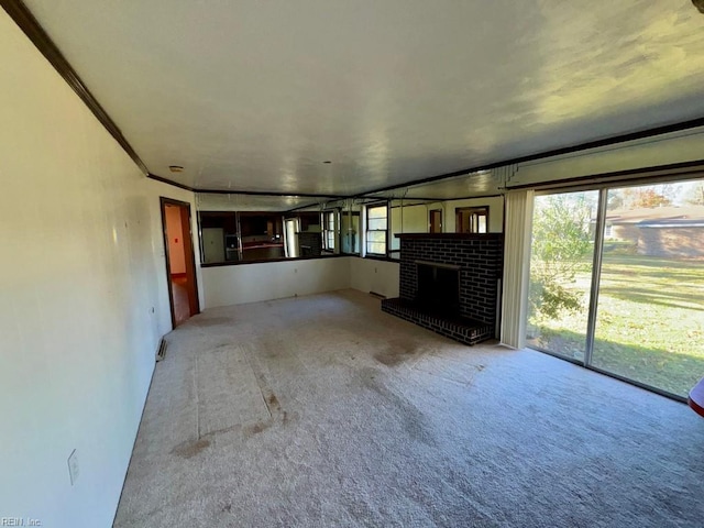 unfurnished living room featuring a fireplace, carpet, and ornamental molding