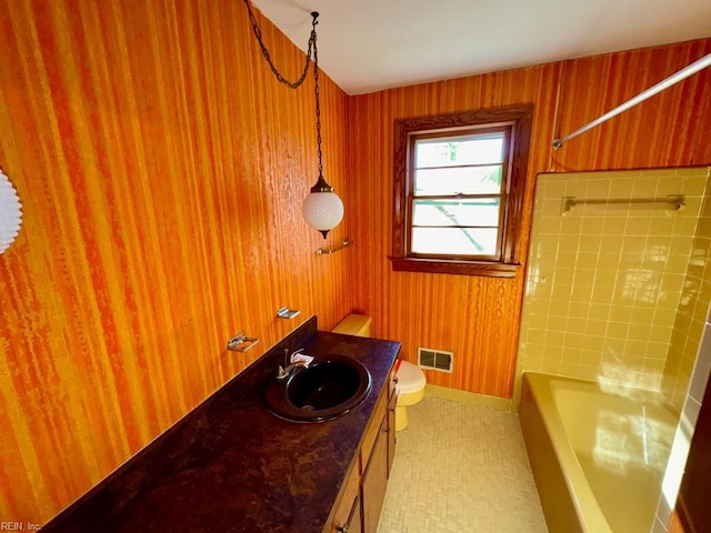 bathroom with vanity, toilet, and wood walls