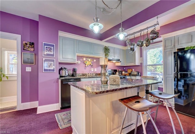 kitchen with dark stone countertops, a breakfast bar, gray cabinetry, and black appliances