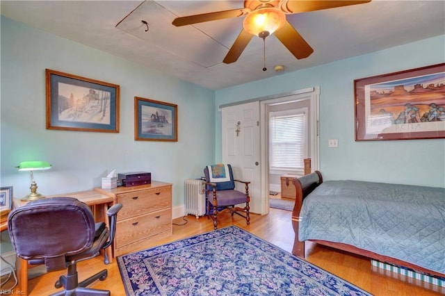 bedroom with radiator heating unit, light wood-type flooring, and ceiling fan