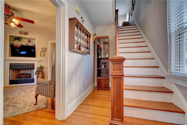 stairs with hardwood / wood-style floors and ceiling fan