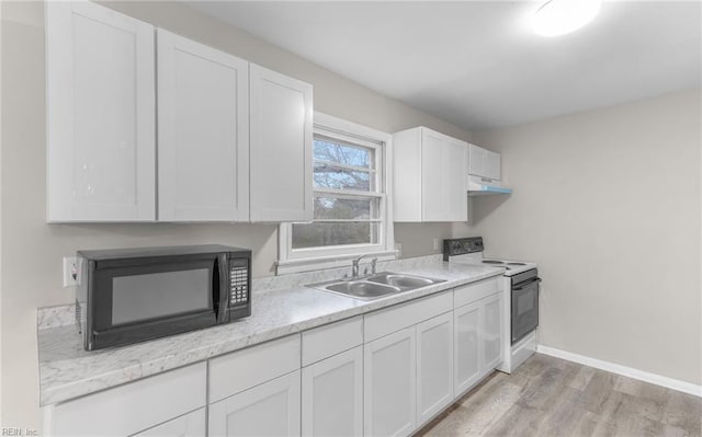 kitchen with white cabinetry, electric range, sink, light stone counters, and light hardwood / wood-style floors