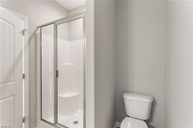 bathroom featuring toilet and a shower with door