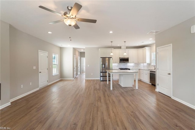 kitchen with a center island, decorative light fixtures, a breakfast bar, white cabinets, and appliances with stainless steel finishes