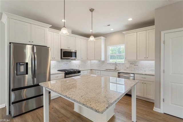 kitchen with a kitchen breakfast bar, sink, pendant lighting, and appliances with stainless steel finishes