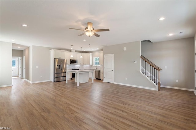 unfurnished living room with wood-type flooring and ceiling fan