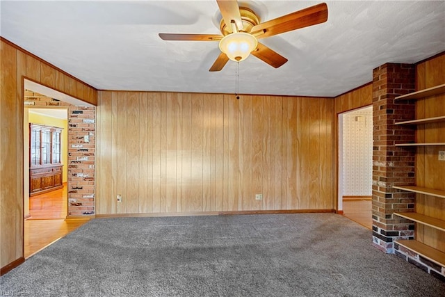 empty room with ceiling fan, carpet, and wood walls