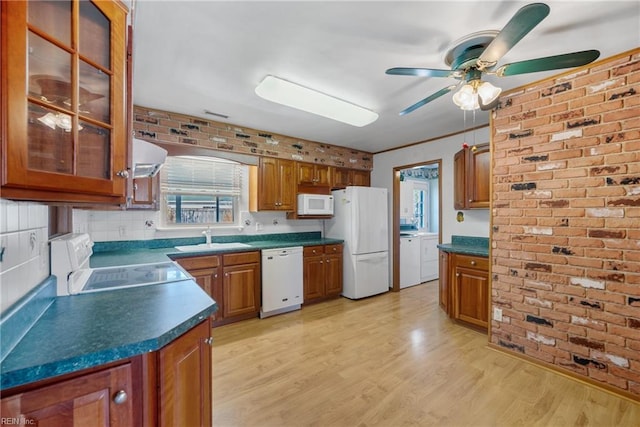 kitchen with sink, white appliances, separate washer and dryer, and brick wall