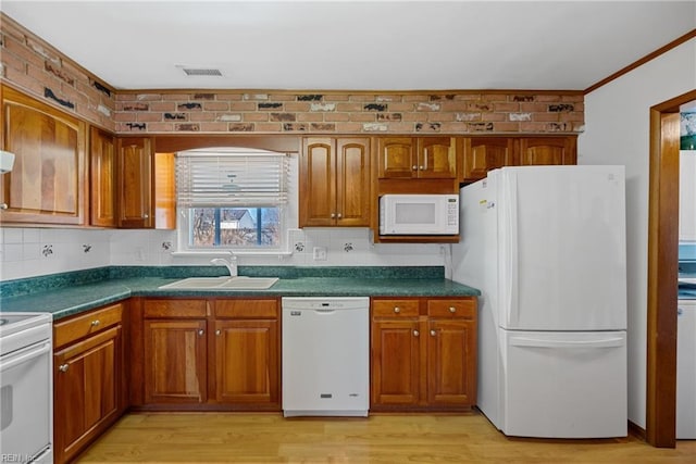 kitchen with brick wall, white appliances, light hardwood / wood-style floors, and sink