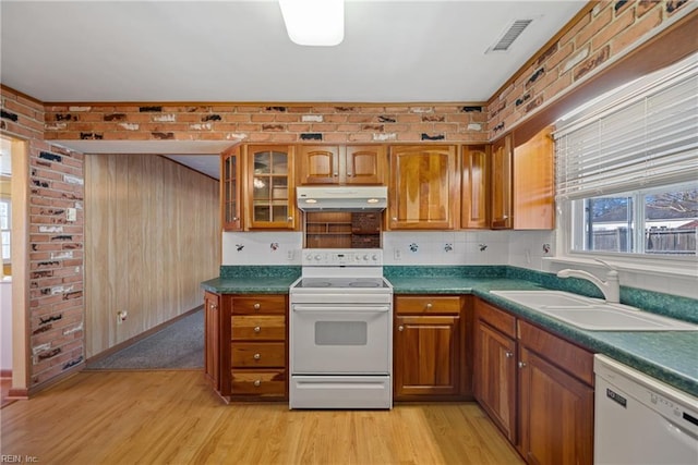 kitchen with light wood-type flooring, white appliances, and brick wall