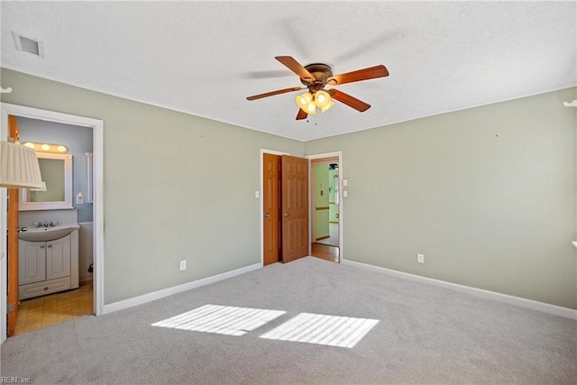 unfurnished bedroom featuring light colored carpet, ensuite bath, ceiling fan, and sink