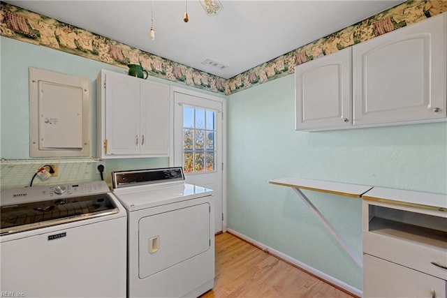 washroom featuring cabinets, electric panel, light hardwood / wood-style flooring, and washer and clothes dryer