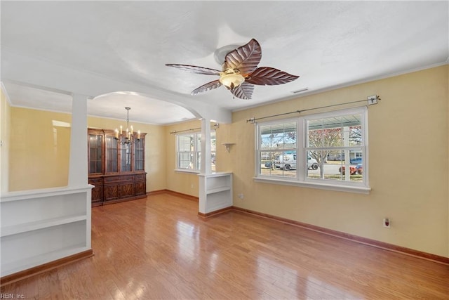 interior space with ceiling fan with notable chandelier, light hardwood / wood-style floors, and decorative columns