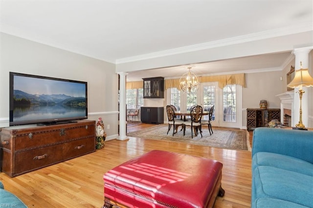 living room with hardwood / wood-style flooring, decorative columns, ornamental molding, and a chandelier