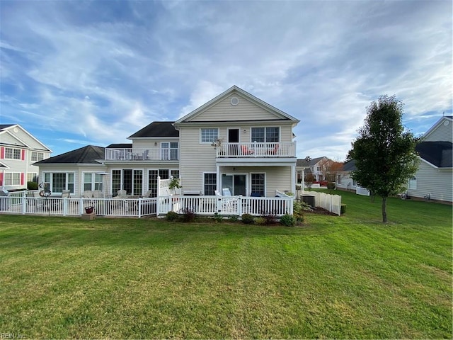 back of house with a lawn and a balcony