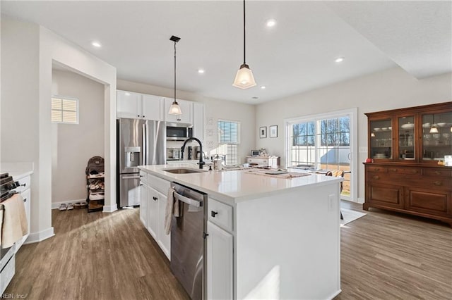 kitchen with sink, white cabinetry, an island with sink, pendant lighting, and appliances with stainless steel finishes