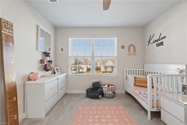 carpeted bedroom with a nursery area and ceiling fan