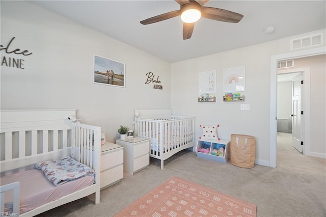 bedroom with a nursery area, light carpet, and ceiling fan