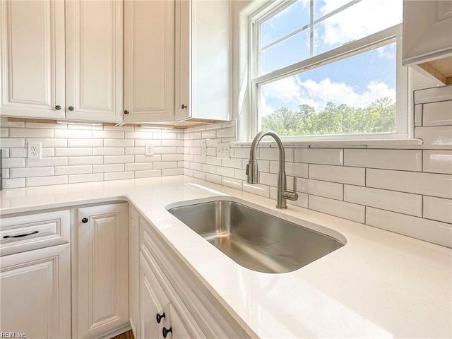 kitchen featuring backsplash, plenty of natural light, white cabinetry, and sink