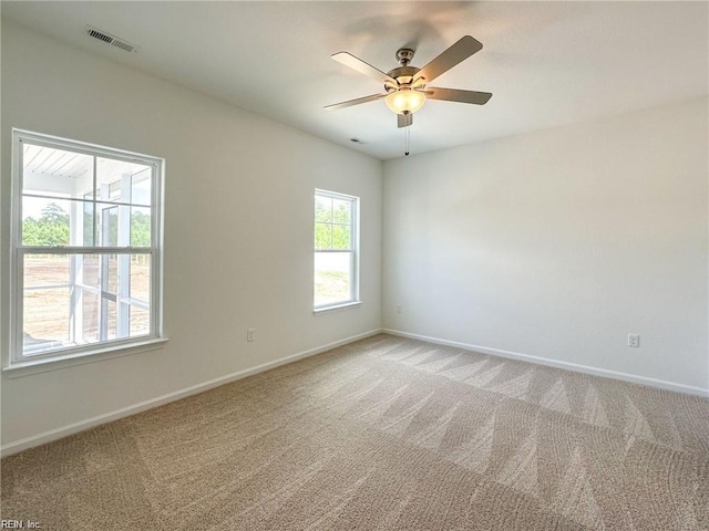 carpeted empty room featuring a wealth of natural light and ceiling fan