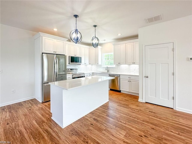 kitchen featuring white cabinets, appliances with stainless steel finishes, light hardwood / wood-style flooring, and a kitchen island