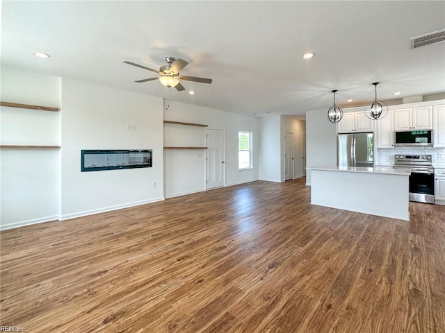 unfurnished living room with ceiling fan with notable chandelier and hardwood / wood-style flooring