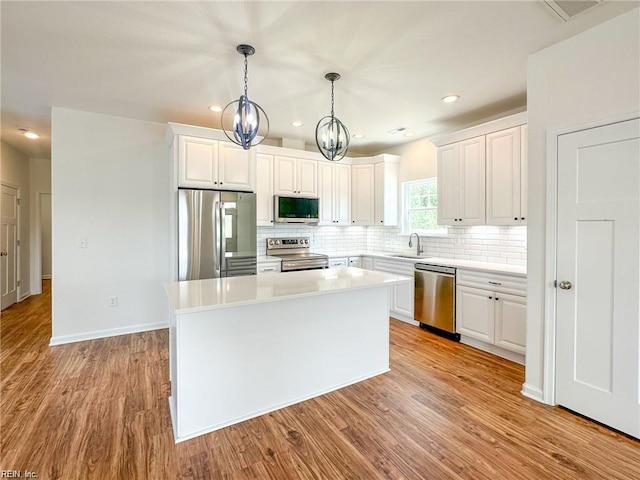 kitchen featuring sink, hanging light fixtures, stainless steel appliances, a chandelier, and white cabinets