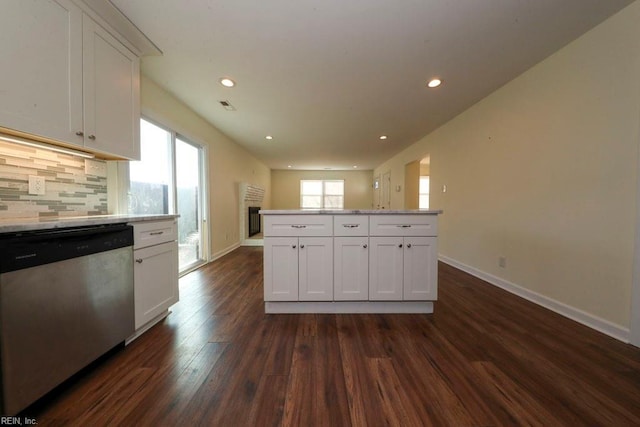 kitchen with a kitchen island, dark hardwood / wood-style flooring, stainless steel dishwasher, backsplash, and white cabinets