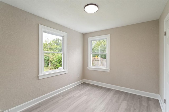 empty room with light hardwood / wood-style floors and plenty of natural light