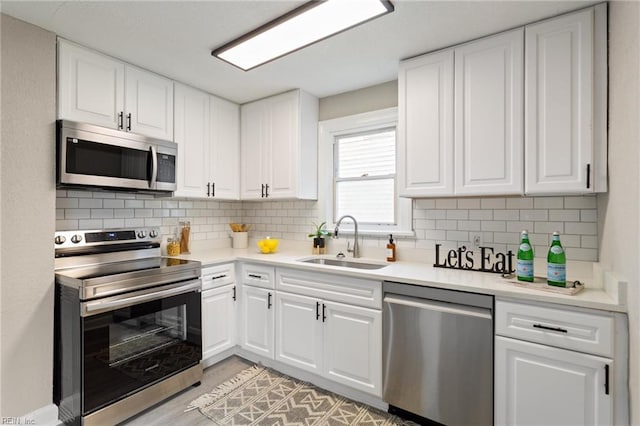 kitchen featuring backsplash, white cabinetry, sink, and stainless steel appliances