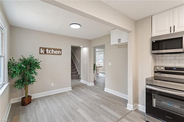 kitchen featuring decorative backsplash, white cabinetry, light hardwood / wood-style flooring, and stainless steel appliances