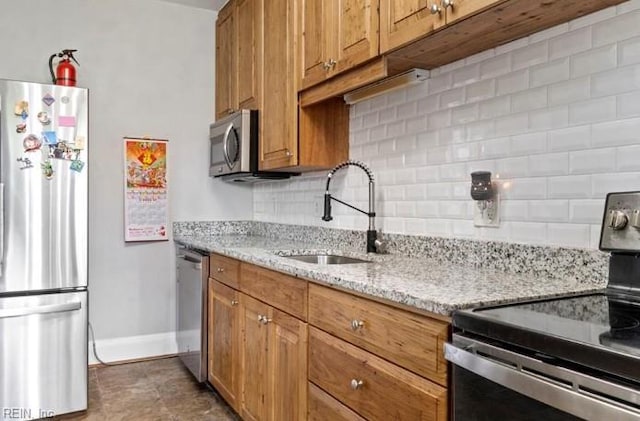 kitchen featuring sink, light stone countertops, stainless steel appliances, and tasteful backsplash