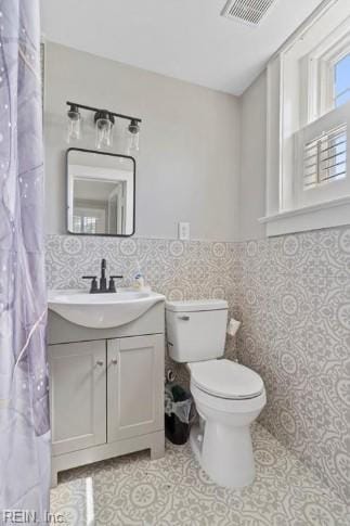 bathroom with vanity, tile walls, and toilet