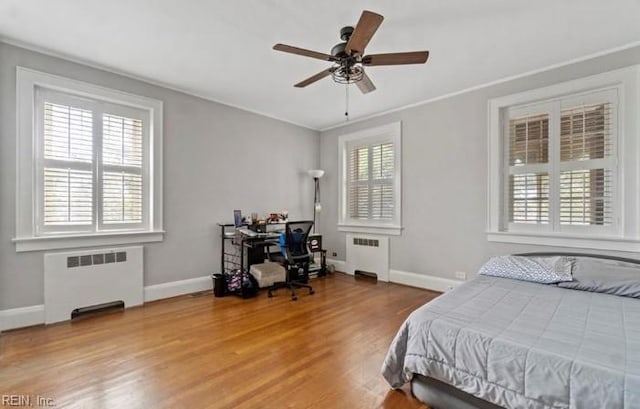 bedroom featuring ceiling fan, radiator heating unit, light hardwood / wood-style floors, and ornamental molding