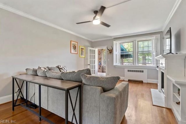 living room featuring radiator heating unit, hardwood / wood-style flooring, ceiling fan, and ornamental molding