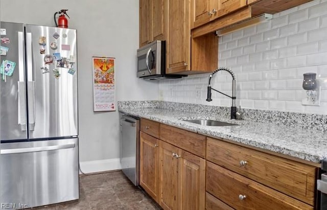 kitchen with backsplash, sink, light stone countertops, and stainless steel appliances