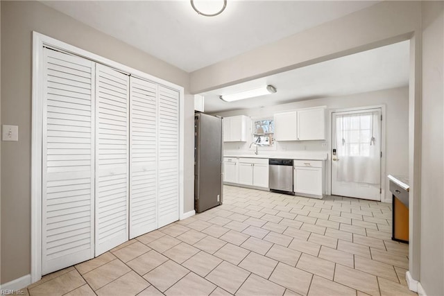 kitchen with sink, white cabinets, light tile patterned flooring, and appliances with stainless steel finishes