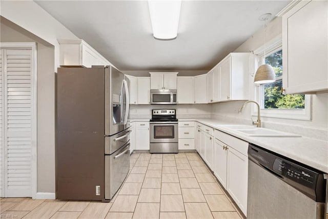 kitchen featuring pendant lighting, white cabinets, sink, and stainless steel appliances