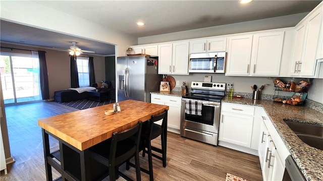 kitchen with ceiling fan, dark stone countertops, white cabinetry, and stainless steel appliances