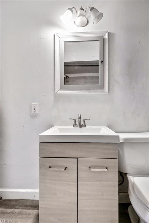 bathroom with hardwood / wood-style flooring, vanity, and toilet