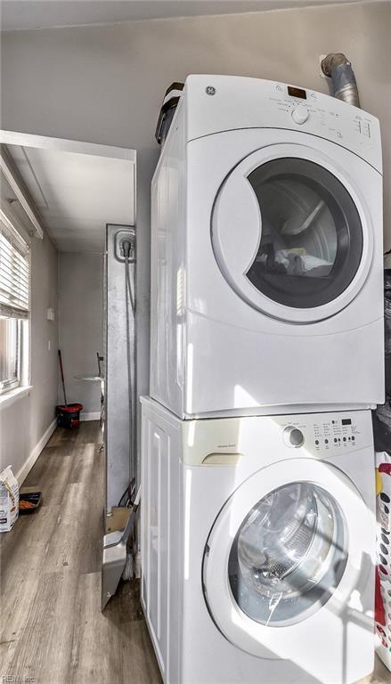 clothes washing area with wood-type flooring and stacked washing maching and dryer