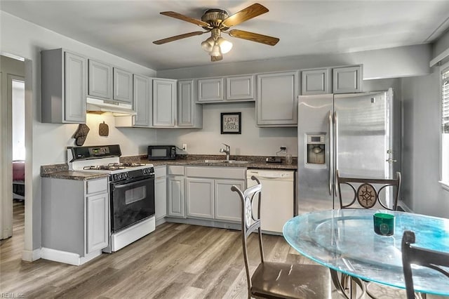 kitchen featuring light wood-type flooring, gray cabinetry, white appliances, ceiling fan, and sink