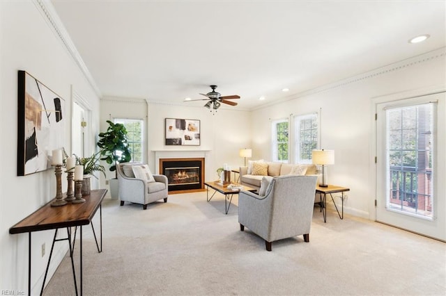 carpeted living room featuring ceiling fan, a healthy amount of sunlight, and ornamental molding