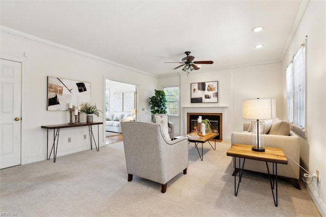 living room featuring ceiling fan, a healthy amount of sunlight, ornamental molding, and light carpet