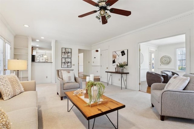 living room with light carpet, crown molding, and ceiling fan