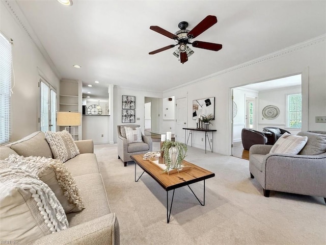 living room with ceiling fan, ornamental molding, and light carpet